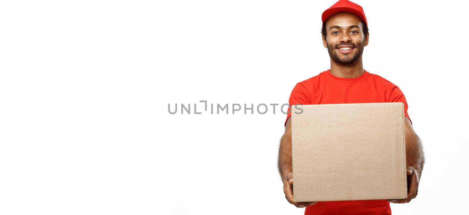 Delivery Concept - Portrait of Happy African American delivery man in red cloth holding a box package. Isolated on white studio Background. Copy Space by Benzoix