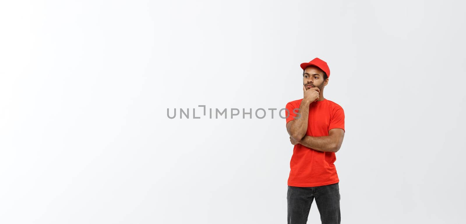 Delivery Concept - Handsome African American delivery man serious thinking of something. Isolated on Grey studio Background. Copy Space. by Benzoix