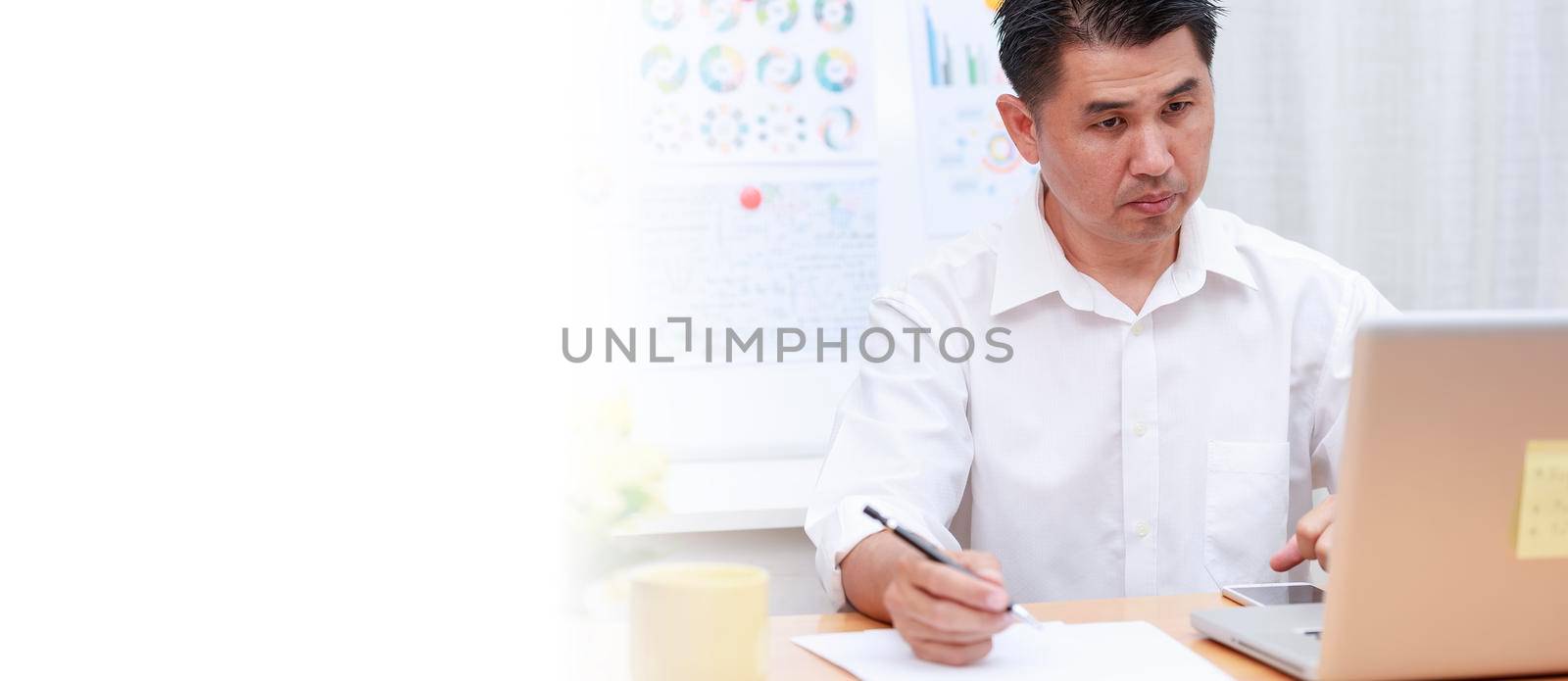 Asian businessman talking with team via video conference writing note on paper. business people using laptop  for online meeting. Business work from home concept.