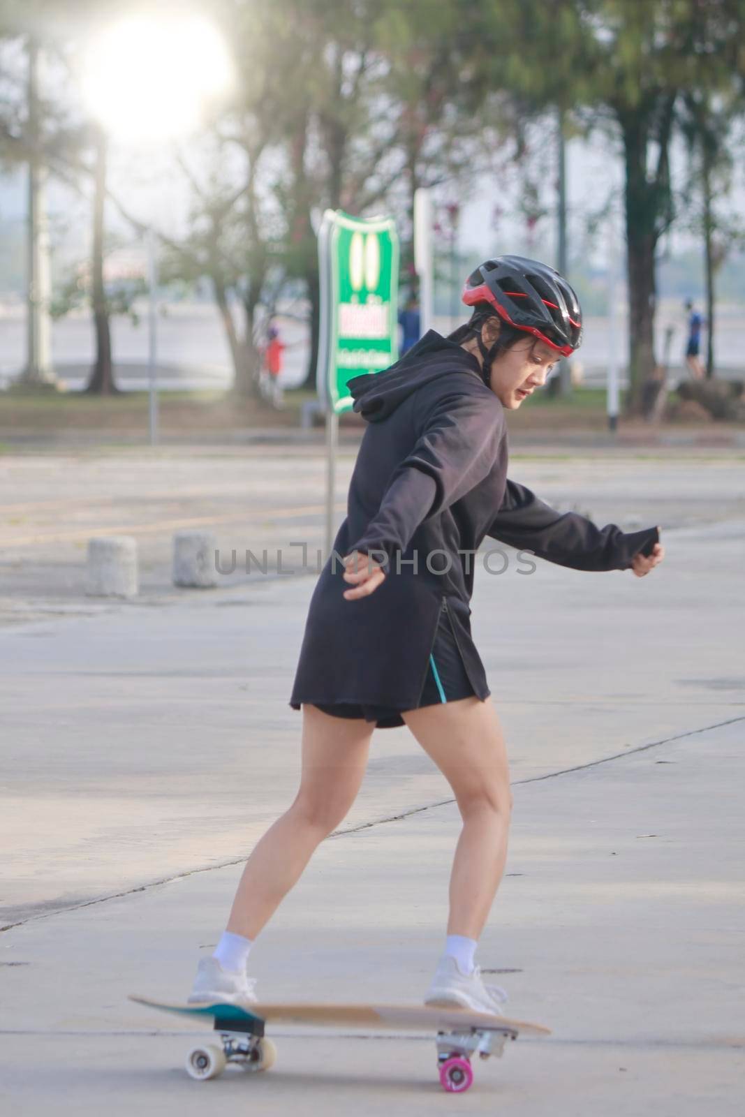 Asian women on skates board outdoors on beautiful summer day. Happy young women play surfskate at park on morning time. Sport activity lifestyle concept
