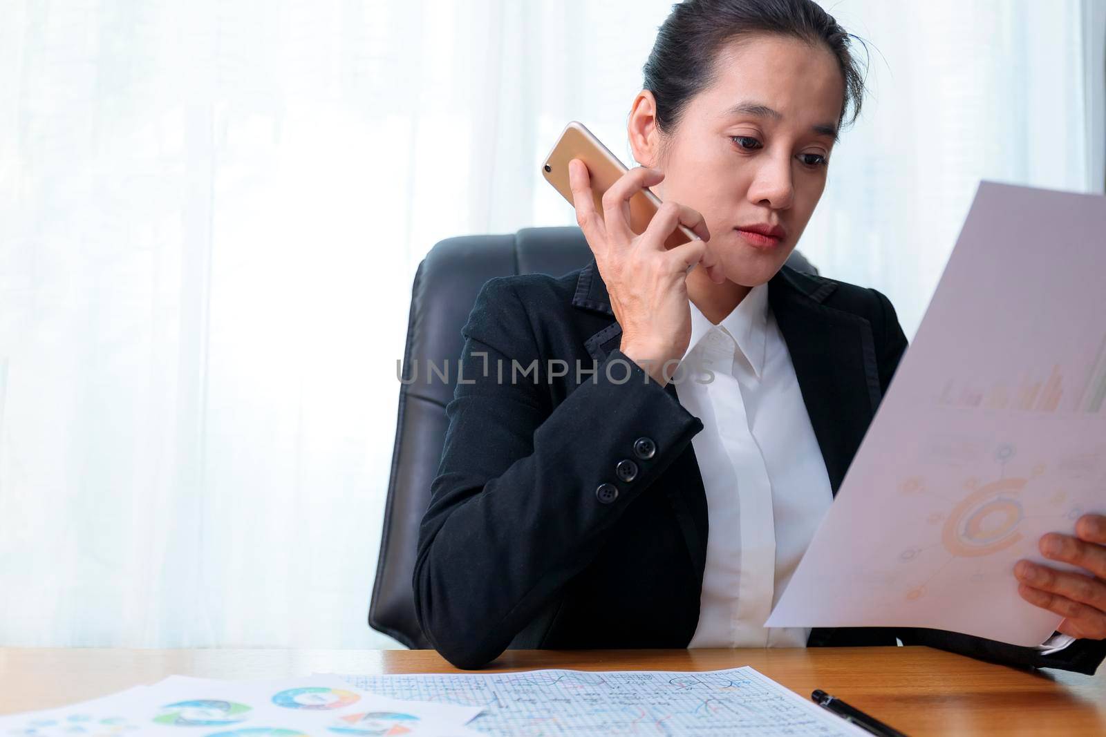 Business women holding smart phone to speak with partners, customers, team and analysis paper chart at office. Business people call for working with customer or partner with smart phone. Business concept.