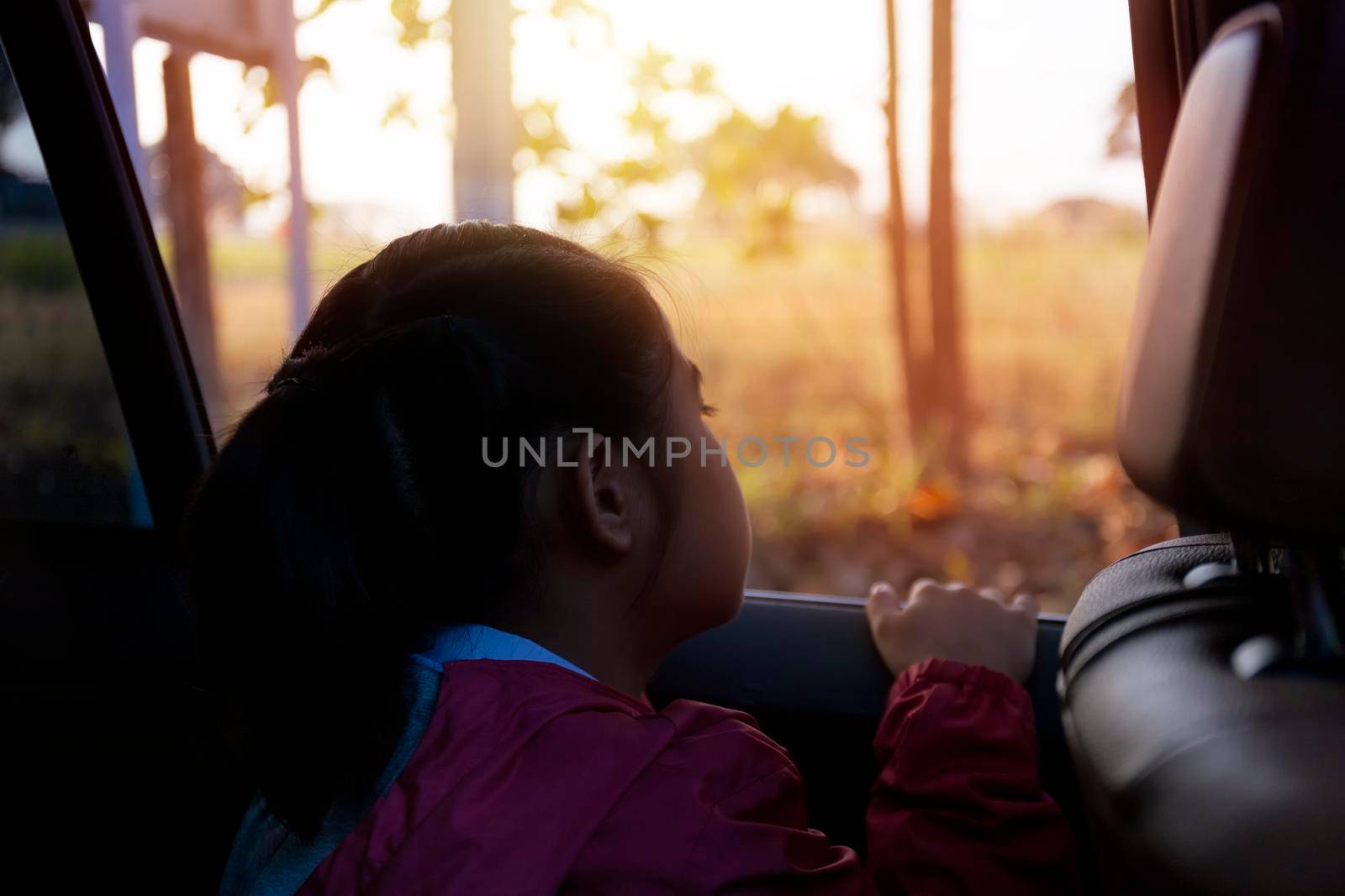 Asian little girl looking something out the car. In the morning, the girl was looking at something outside the car window on the way to school. children relax with street view from the car. Family in car concept.