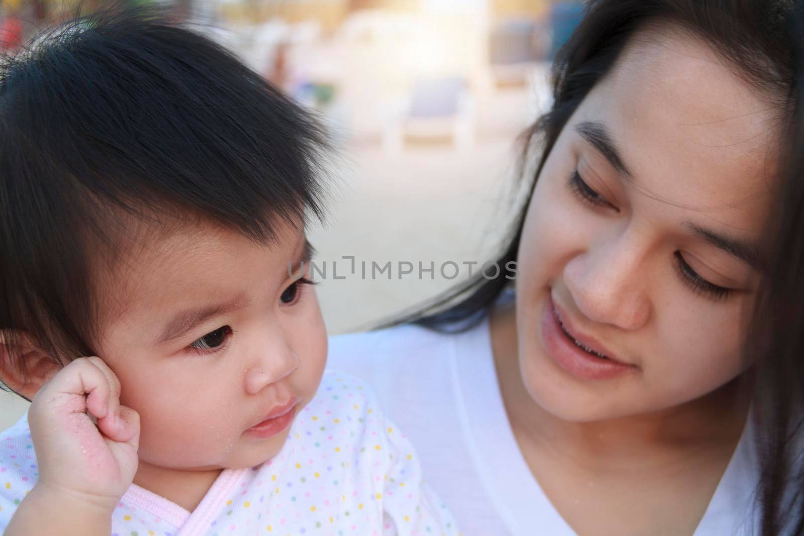 Close up Portrait of happy Asian mother and daughter. Asian woman and little toddler girl in the playground park. Happy family playing together at playground park