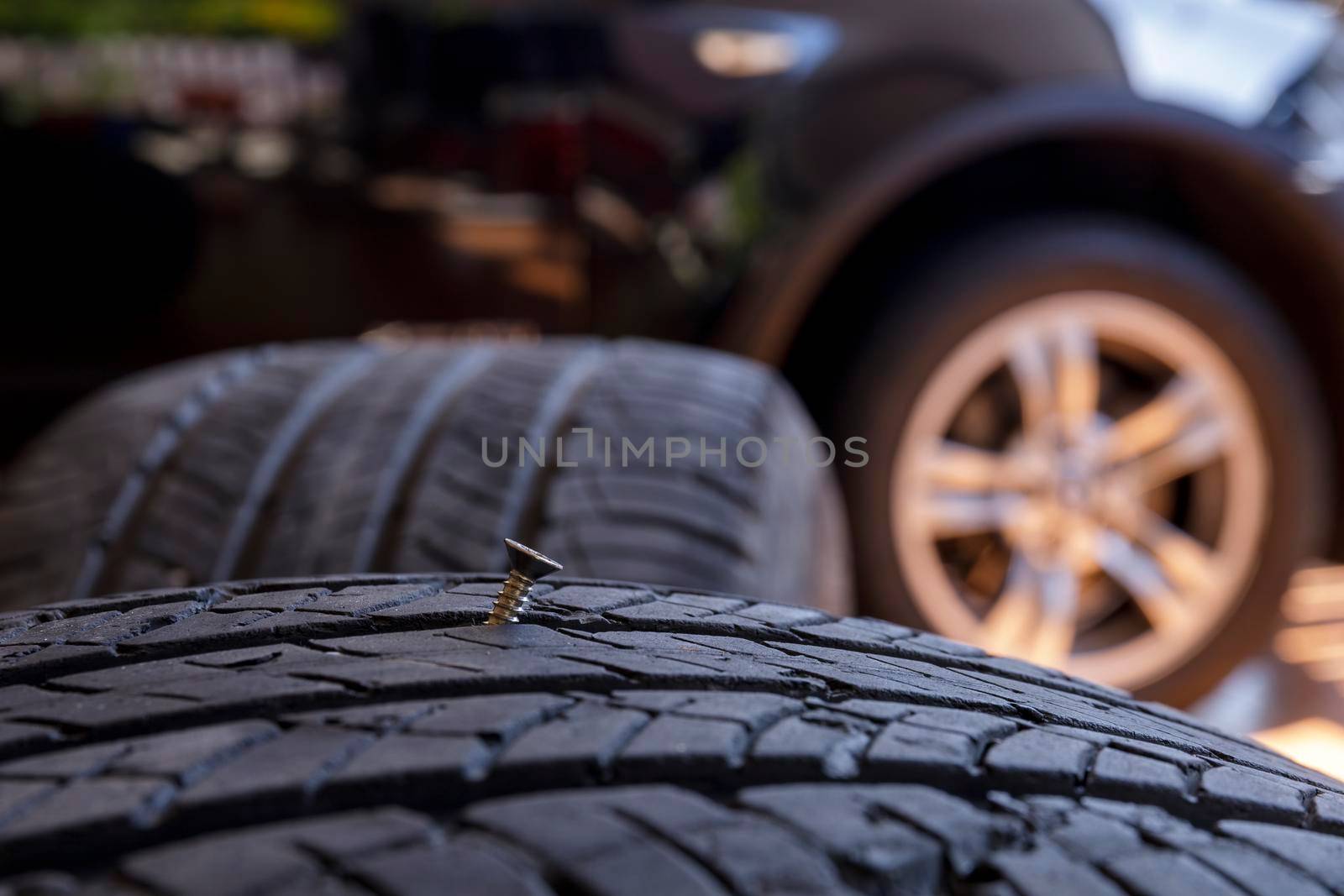 Close up old tire have nails nut or screw drive stuck in side. Tire workshop and change old wheel on the car. Used car tires stacked in piles at tire fitting service repair shop