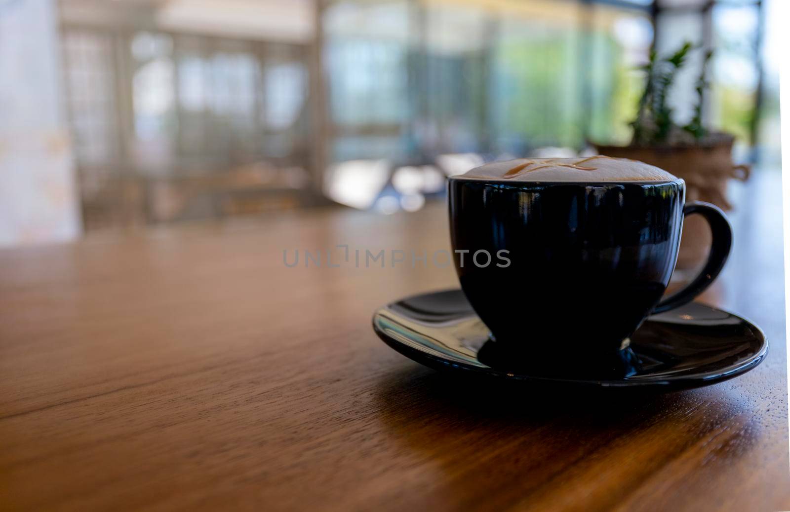 Close up hot cappuccino, latte, caramel macchiato on table with blur coffee shop background. Process with warm vintage tone style. 