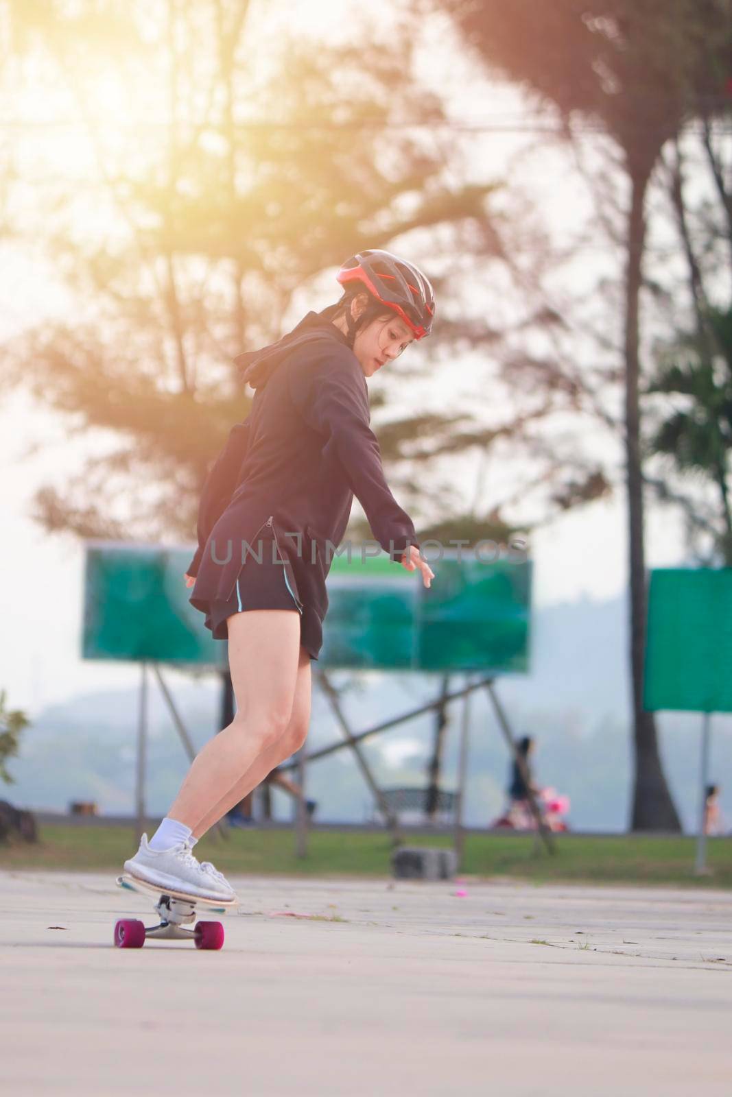 Asian women on skates board outdoors on beautiful summer day. Happy young women play surfskate at park on morning time. Sport activity lifestyle concept