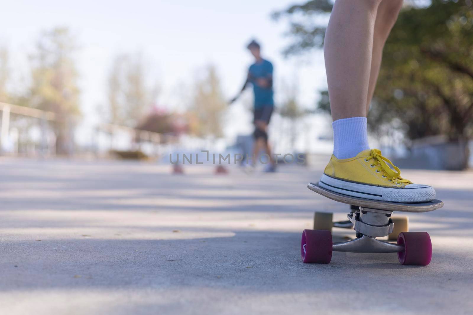 Close-up and motion movement Asian women surf skate or skateboard outdoors on beautiful morning. Happy young women play surf skate at park on morning time. Close up Asian women leg wear sneaker paly surf skate on public park. Sport concept