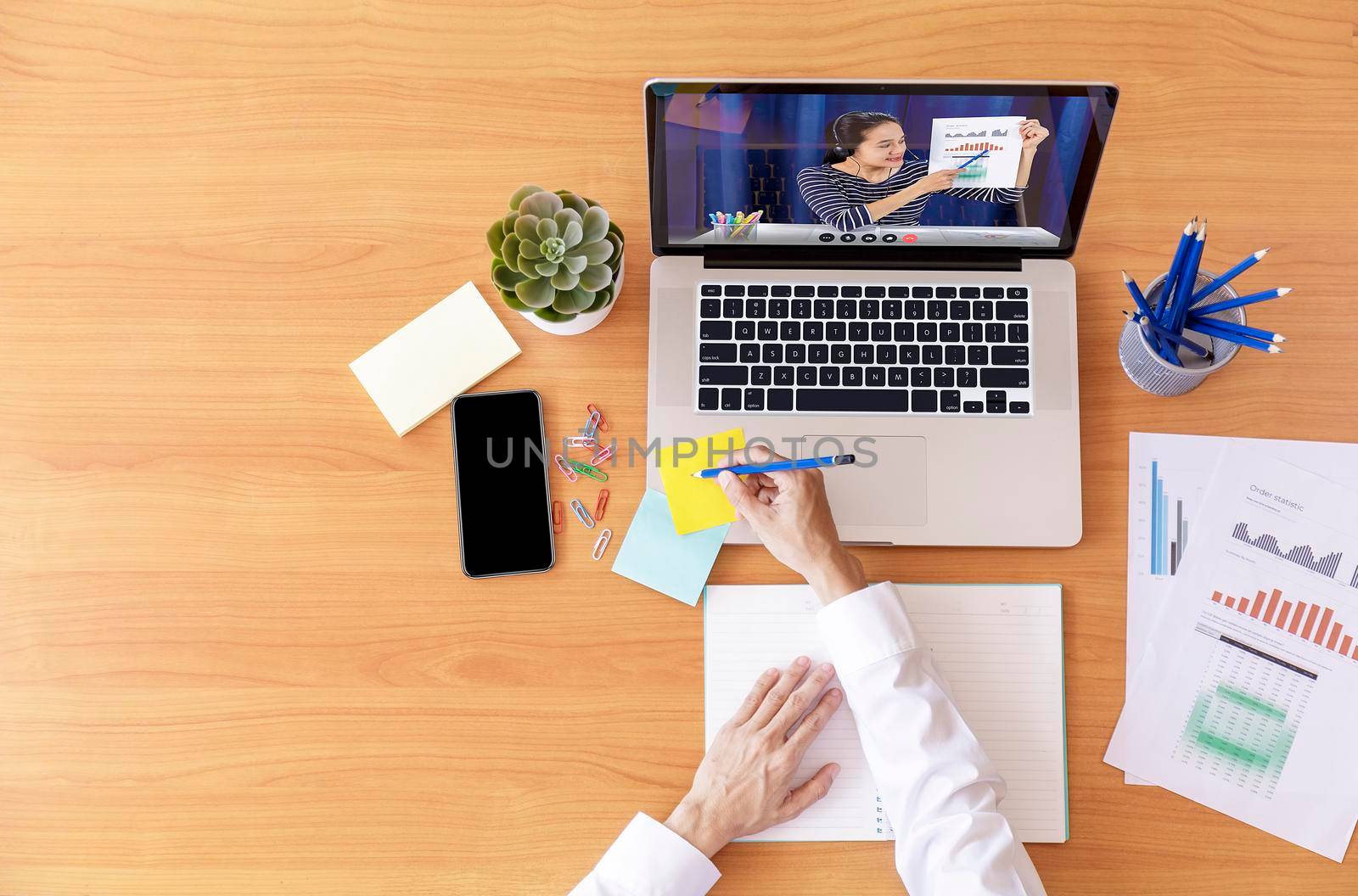 Top view Businessman and businesswoman analysis financial chart with videoconference online meeting. Hand of businesswomen using laptop meeting with diverse colleagues. Covid-19 working from home. 