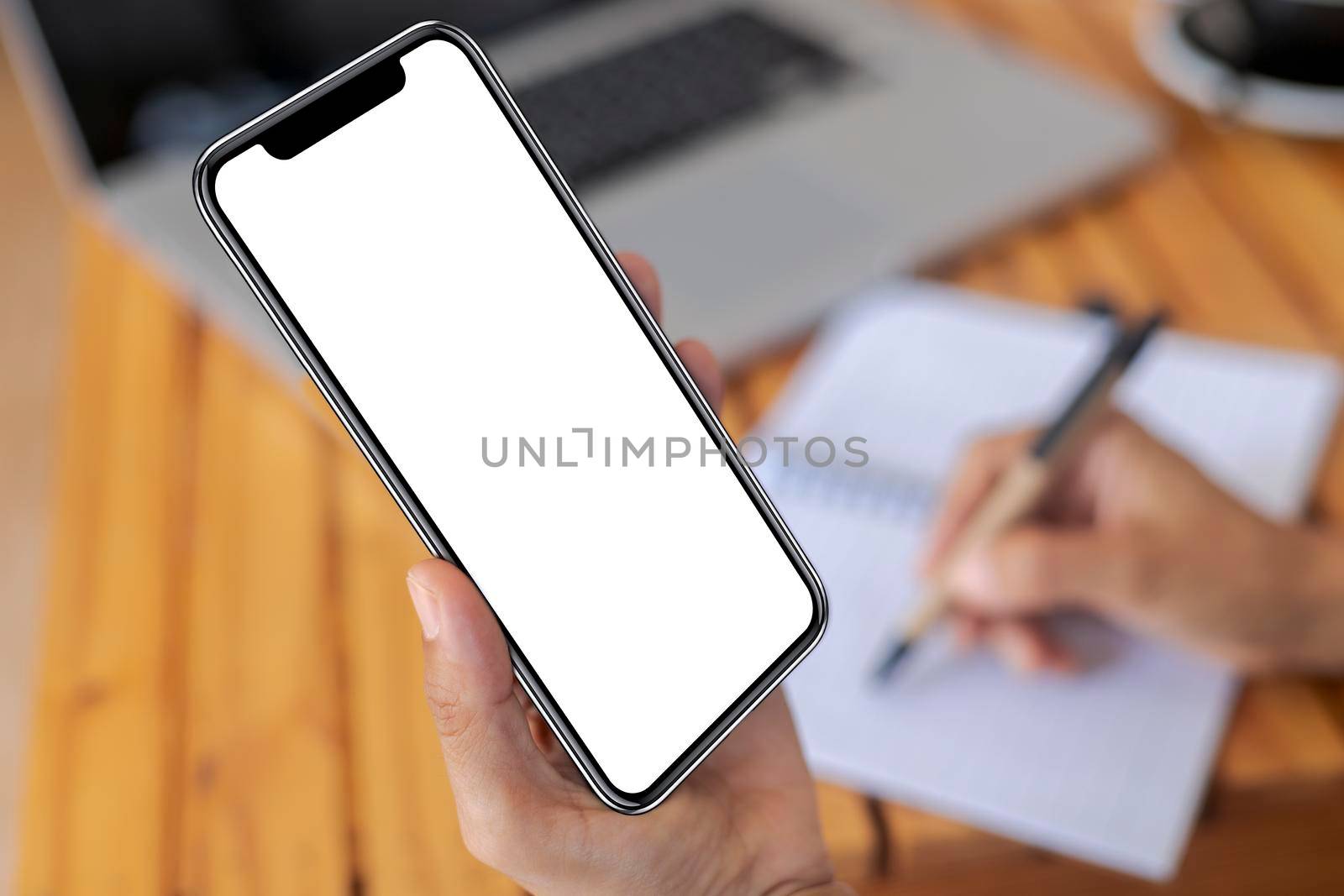 Top view female hands holding smart phone with blank white screen. Women hands workspace, close-up hand holding smartphone blank screen for text and content on wood table background.