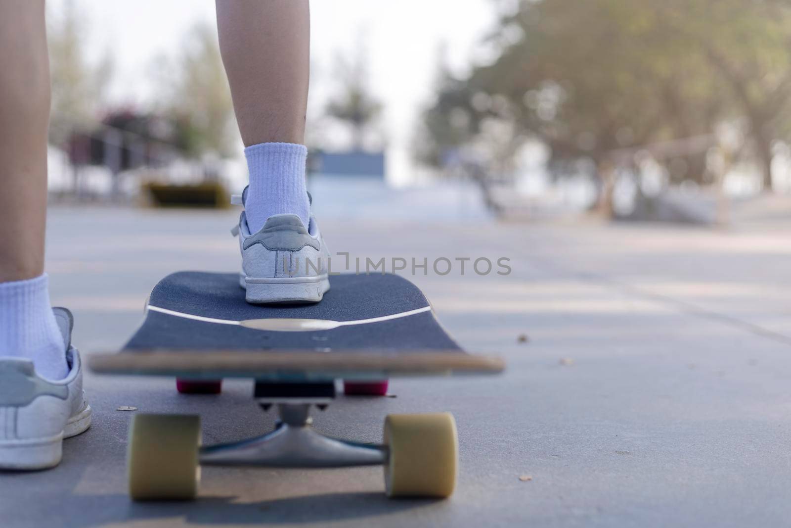 Close-up Asian women surf skate or skateboard outdoors on beautiful morning. Happy young women play surf skate at ramp park on morning time. Close up Asian women leg wear sneaker play surf skate on public park. Sport concept