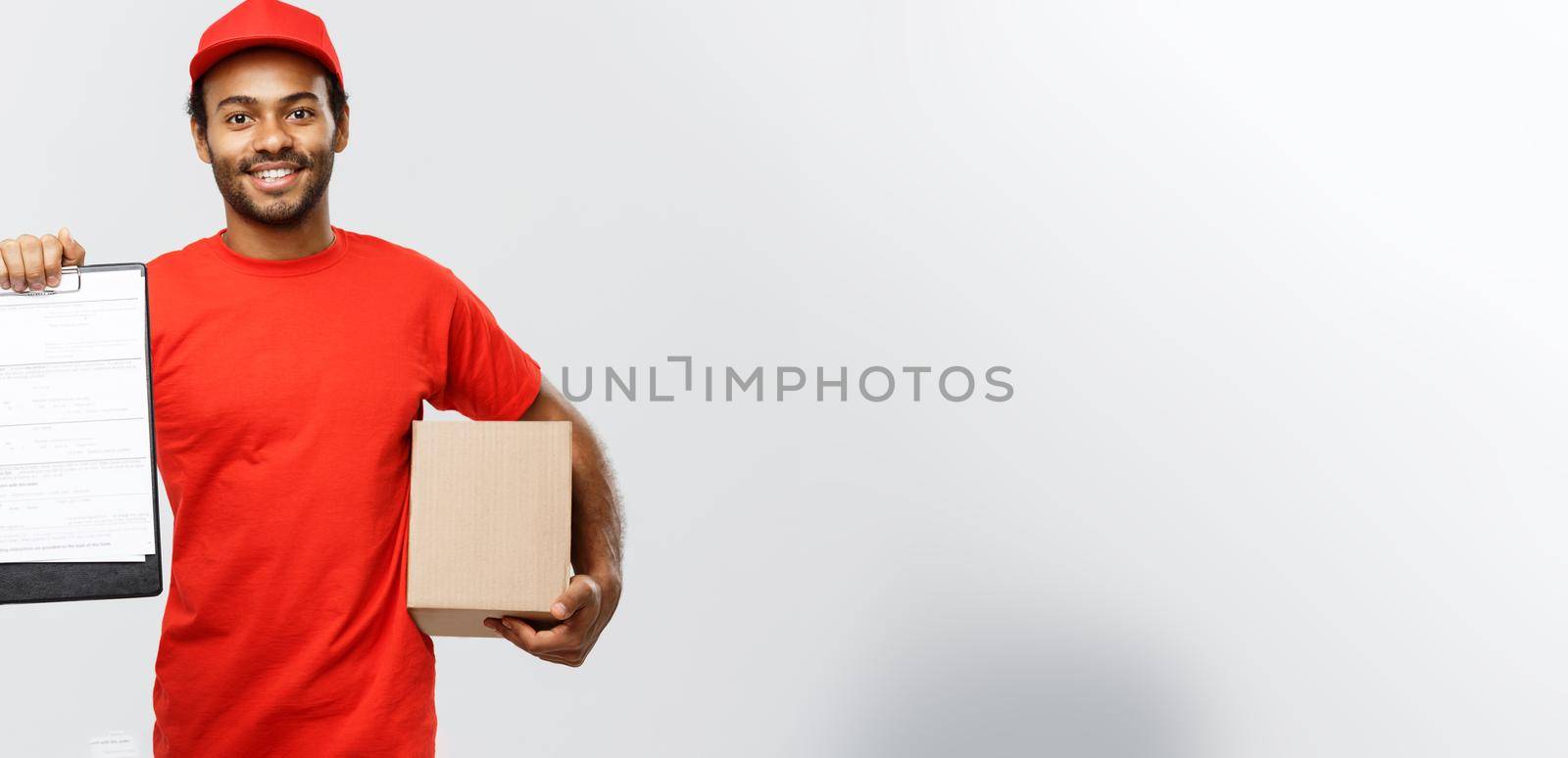 Delivery Concept - Portrait of Handsome African American delivery man or courier showing a confirmation document form to sign. Isolated on Grey studio Background. Copy Space