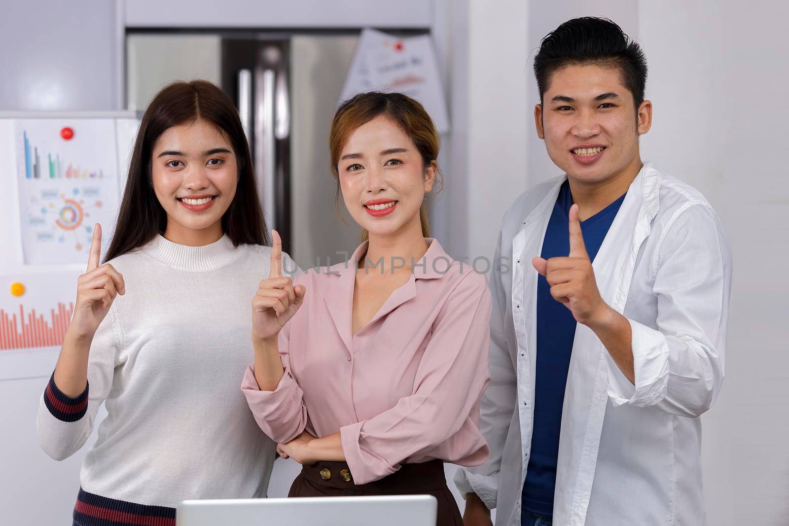 Business Team brainstorm meeting. Group of business people working at Private Home Office.Young business people show index finger .Asian teamwork business people successful celebrate