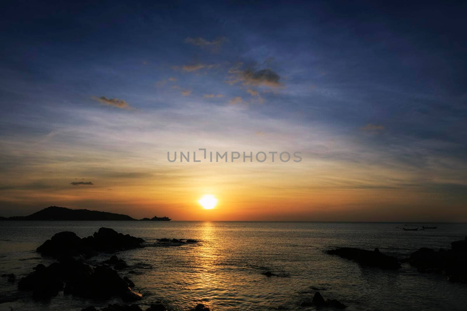 Beautiful sunset over the clam sea with cloud sky background. Sunset over tropical beach. Nature summer  concept. Peak sunset over sea with yellow light reflect on sea water. Tranquil seascape. Horizon over the water.