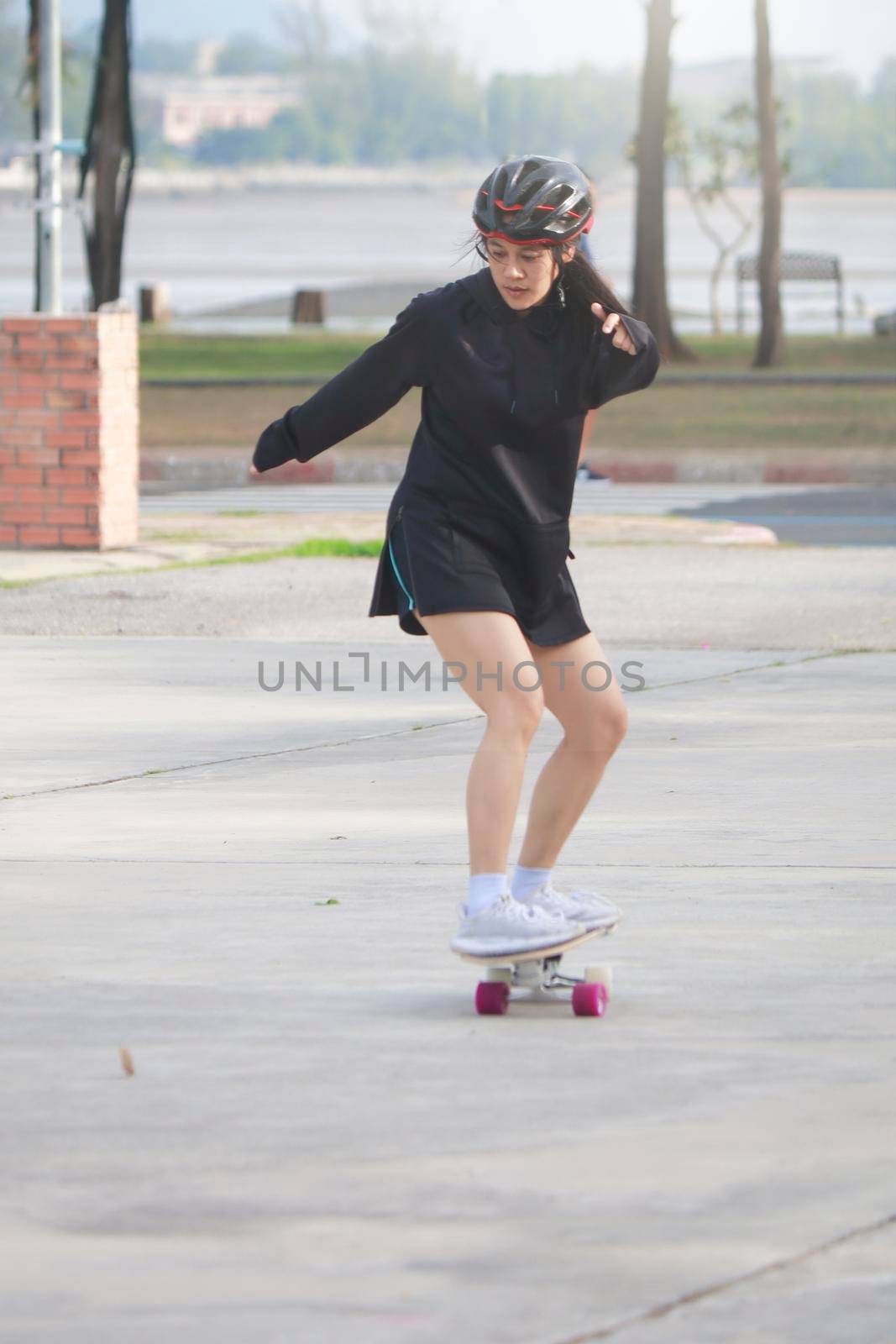 Asian women on skates board outdoors on beautiful summer day. Happy young women play surfskate at park on morning time. Sport activity lifestyle concept