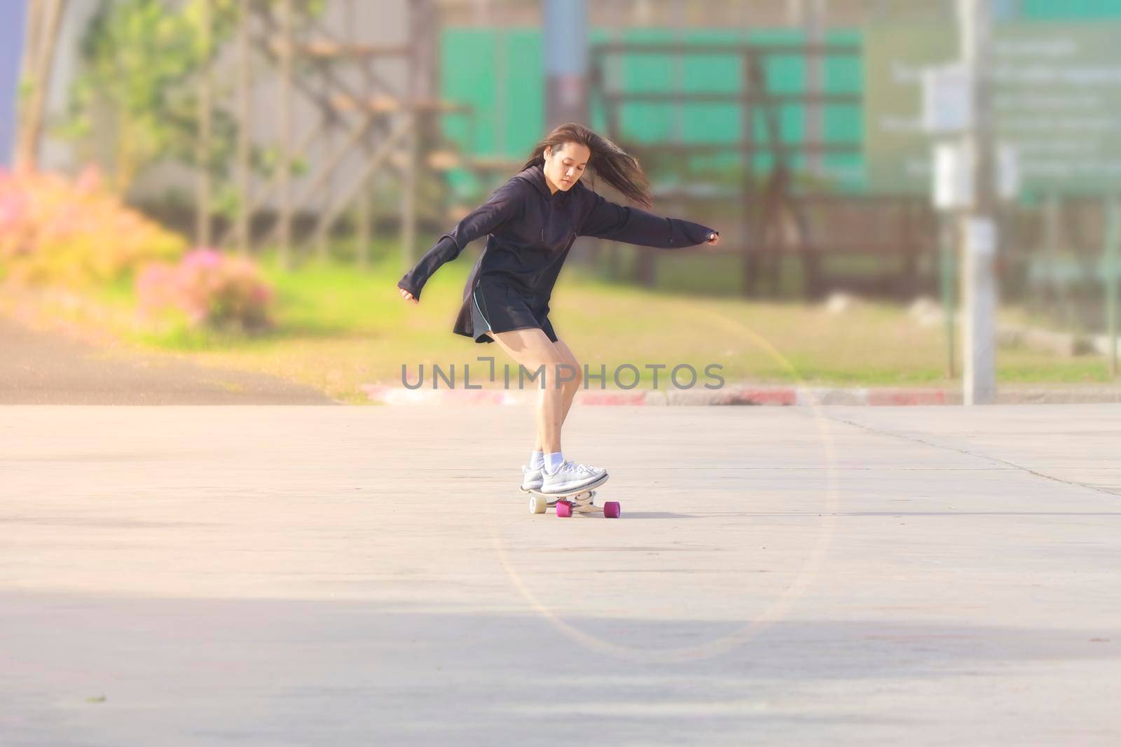 Asian women on skates board outdoors on beautiful summer day. Happy young women play surfskate at park on morning time. Sport activity lifestyle concept