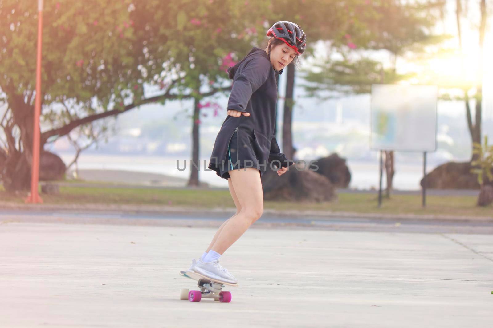 Asian women on skates board outdoors on beautiful summer day. Happy young women play surfskate at park on morning time. Sport activity lifestyle concept