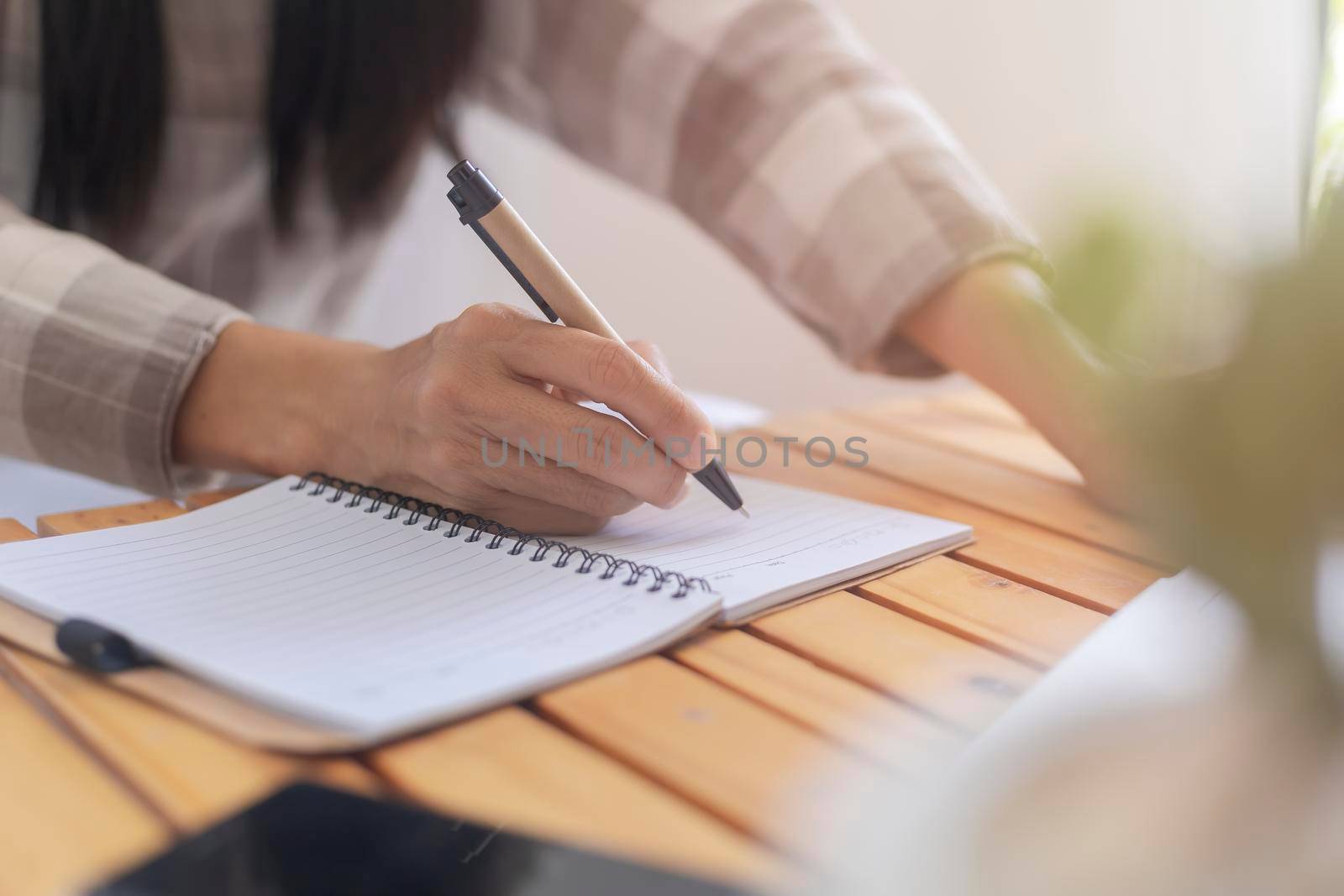 Close up hand of business women use pen writing document paper. Female hand close up writing with a blue pen on a white sheet. Woman writes information on a piece of paper. by Satrinekarn