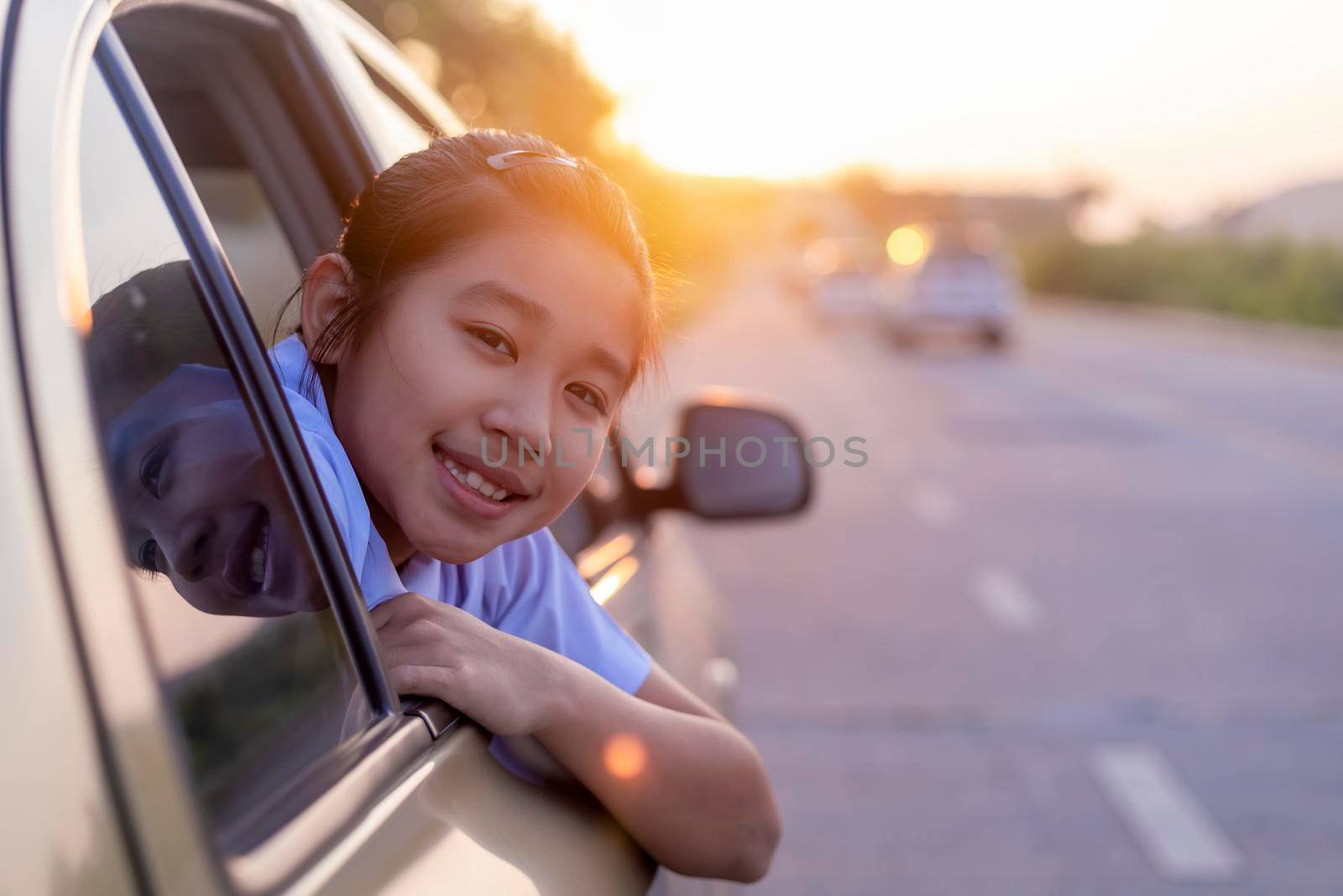 Asian little girl looking something out the car. In the morning, the girl was looking at something outside the car window on the way to school. children relax with street view from the car. Family at car concept. by Satrinekarn