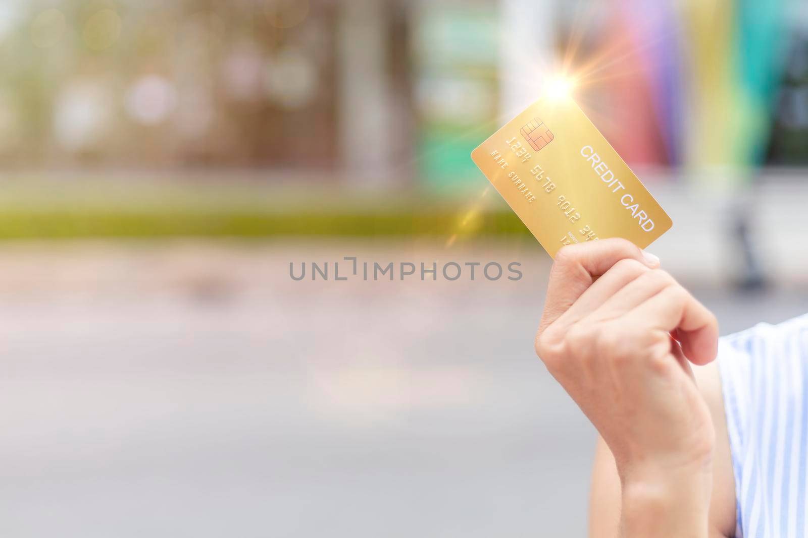 Women hand holding gold credit card member card over blur department store background. Business, shopping, lifestyle concept. With copy space