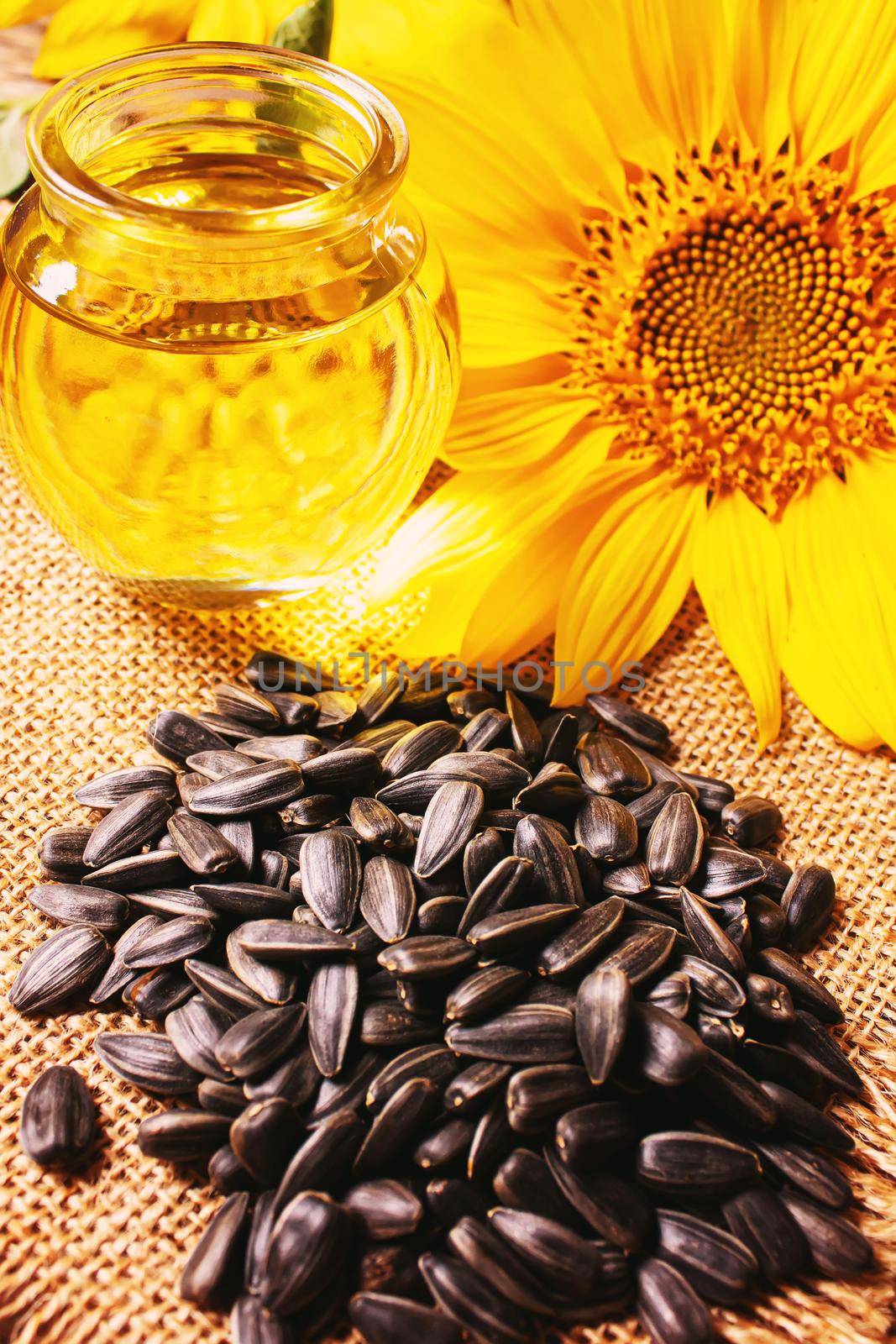 Sunflower seeds and oil bottle on old wooden background. Selective focus by mila1784