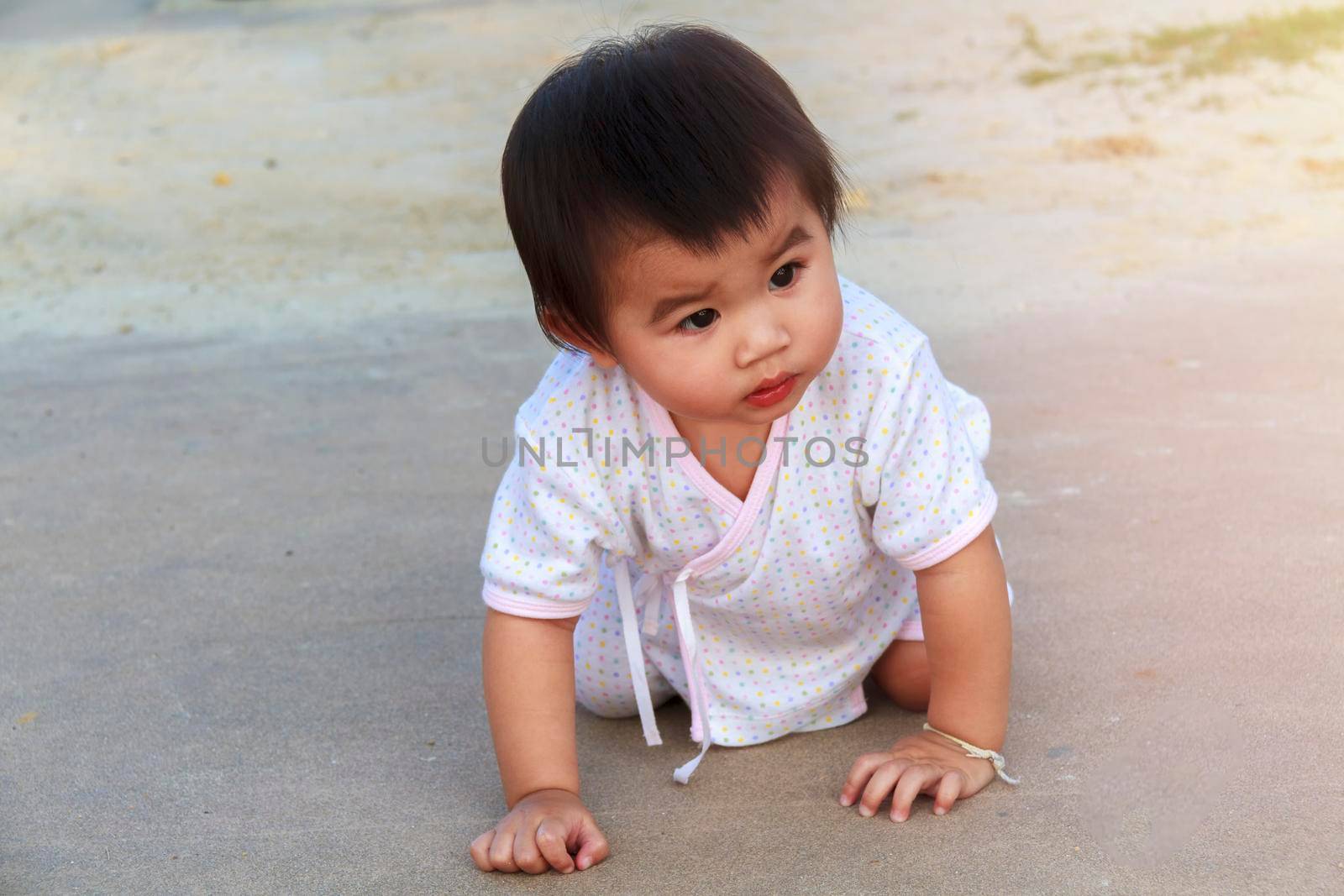 Small baby, little girl creeping, playing on road and sant at beach. Cute baby try to creeping and play on outdoor park. Little girl happy to creeping play at park.