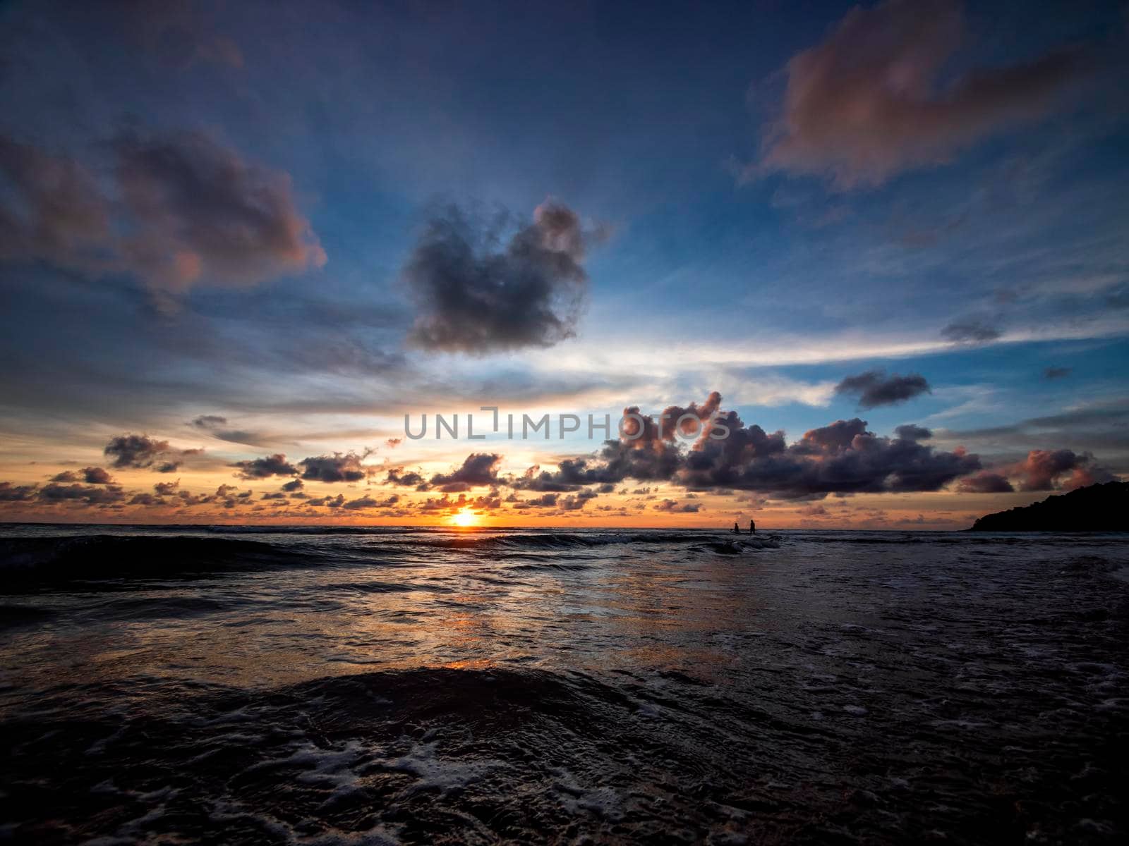 Beautiful sunset over the calm sea with cloud sky background. Sunset over tropical beach. Nature summer  concept. Peak sunset over sea with yellow light reflect on sea water. Tranquil seascape.