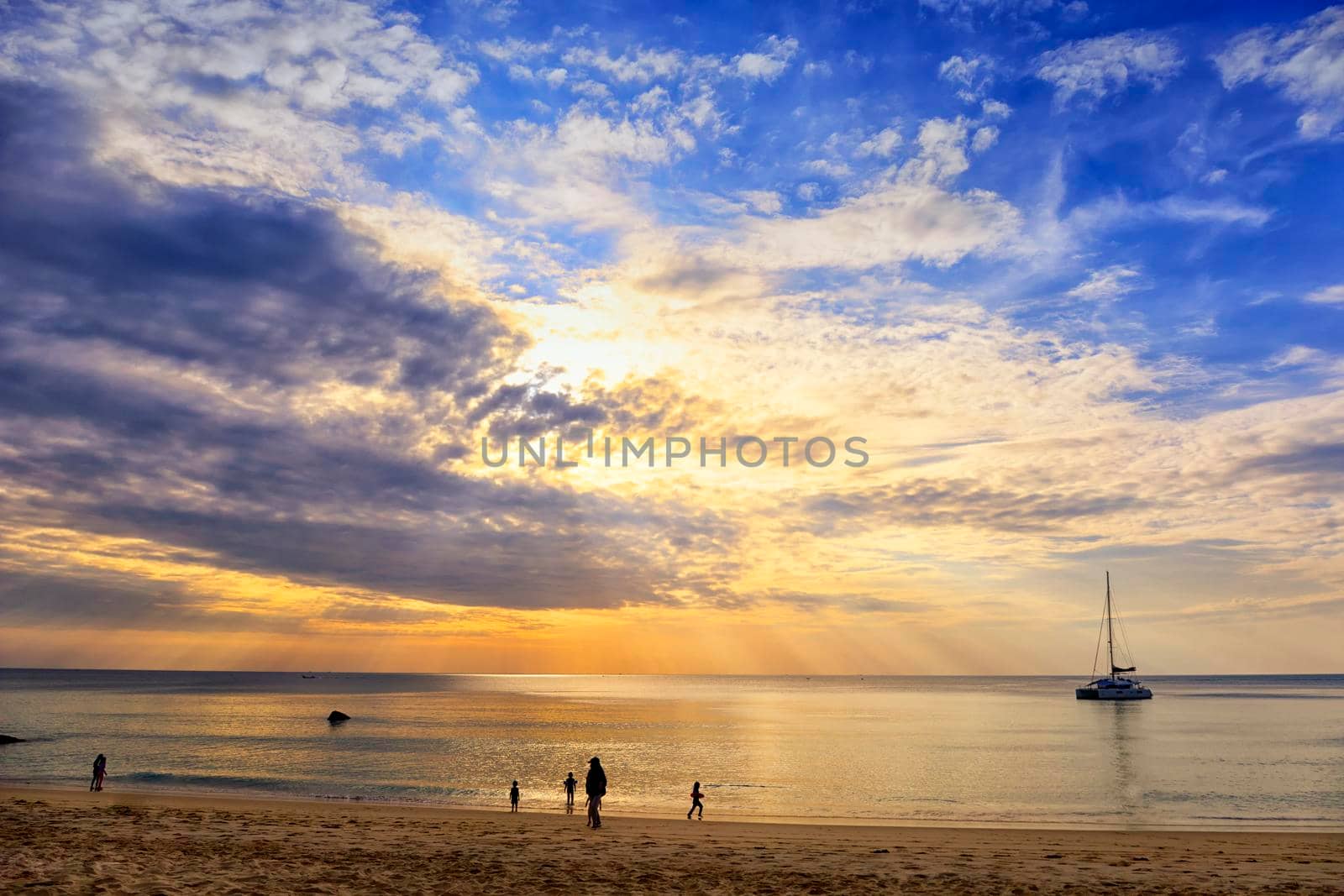 Beautiful sunset over the clam sea with cloud and sky background. Sunset over tropical beach. Nature summer  concept. Sunset and sun ray over the sea withy acht boat and relax people.
