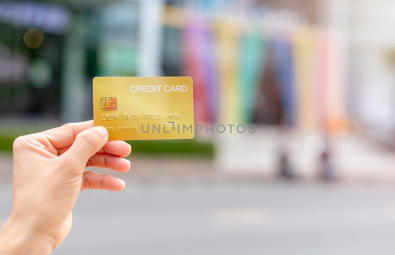 Women hand holding gold credit card member card over blur department store background. Business, shopping, lifestyle concept. With copy space