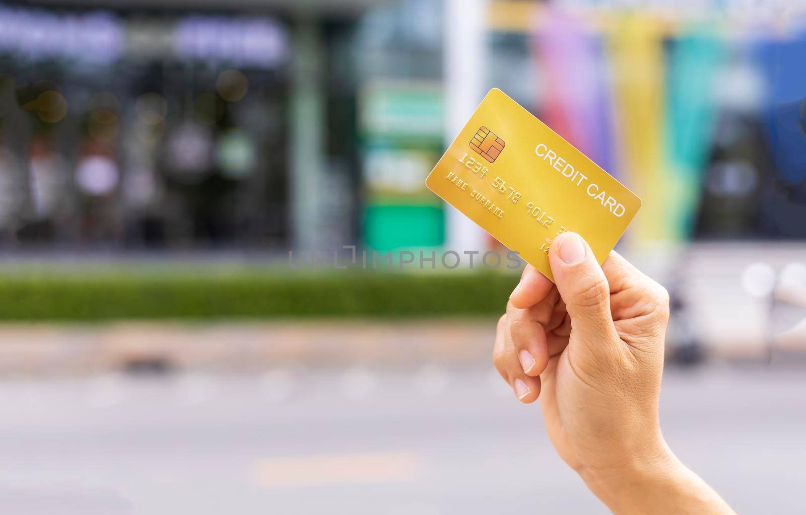 Women hand holding gold credit card member card over blur department store background. Business, shopping, lifestyle concept. With copy space