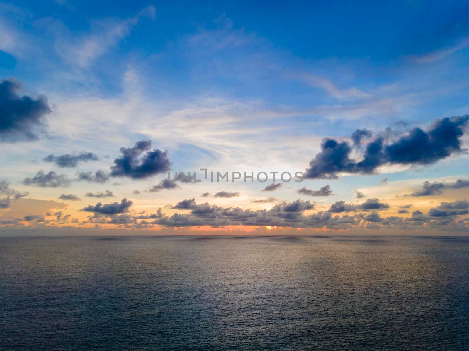 Beautiful sunset over the clam sea with cloud and sky background. Sunset over tropical beach. Nature summer  concept. Peak sunset over sea with yellow light reflect in cloud.