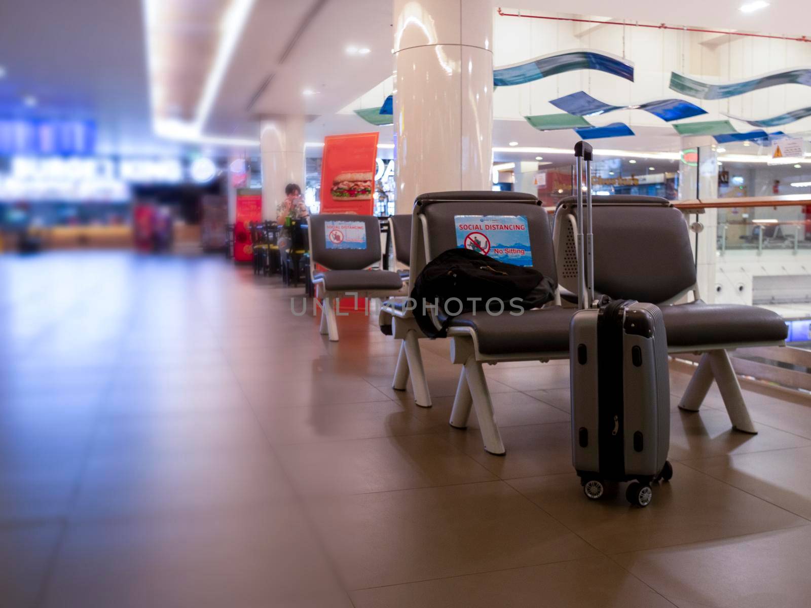 Backpack and travel bag on chair in international airport. Public chair at airport have sign Social distancing protection Coronavirus disease (Covid-19) infection . New normal, travel bubble and social distancing concepts,