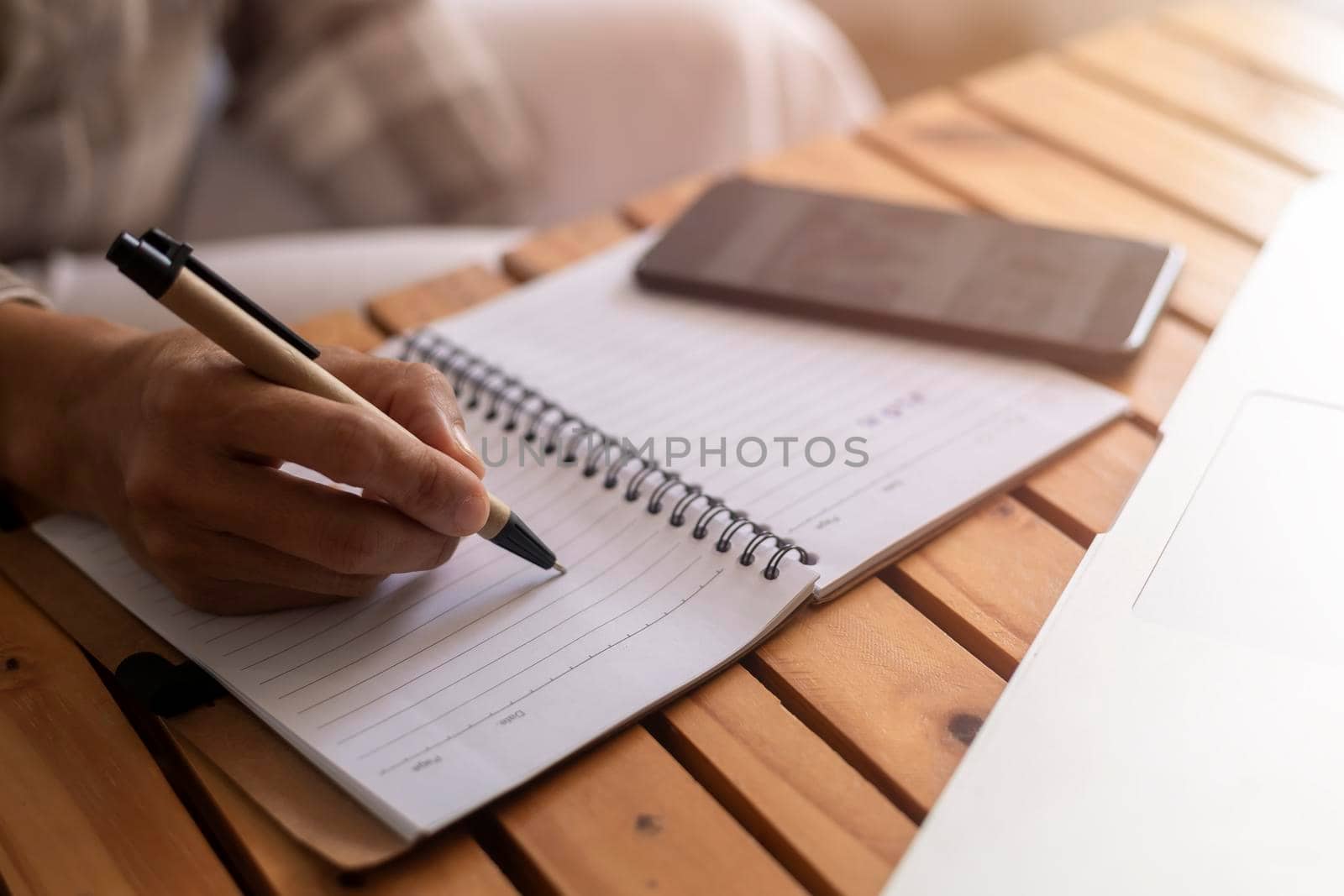 Close up young business woman hands with pen writing notes on paper. female executive sitting at table at home office. Woman's hands writing in spiral notepad placed on wooden table