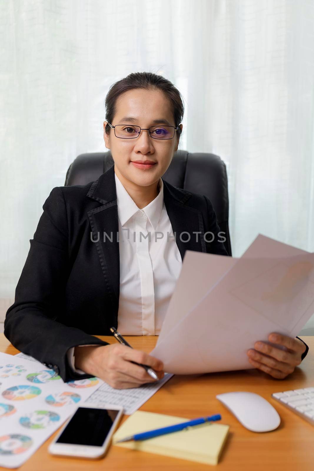 Business women smileing wear glasses holding document paper chart sitting at office. business people using computer PC  at office. Business at home concept.