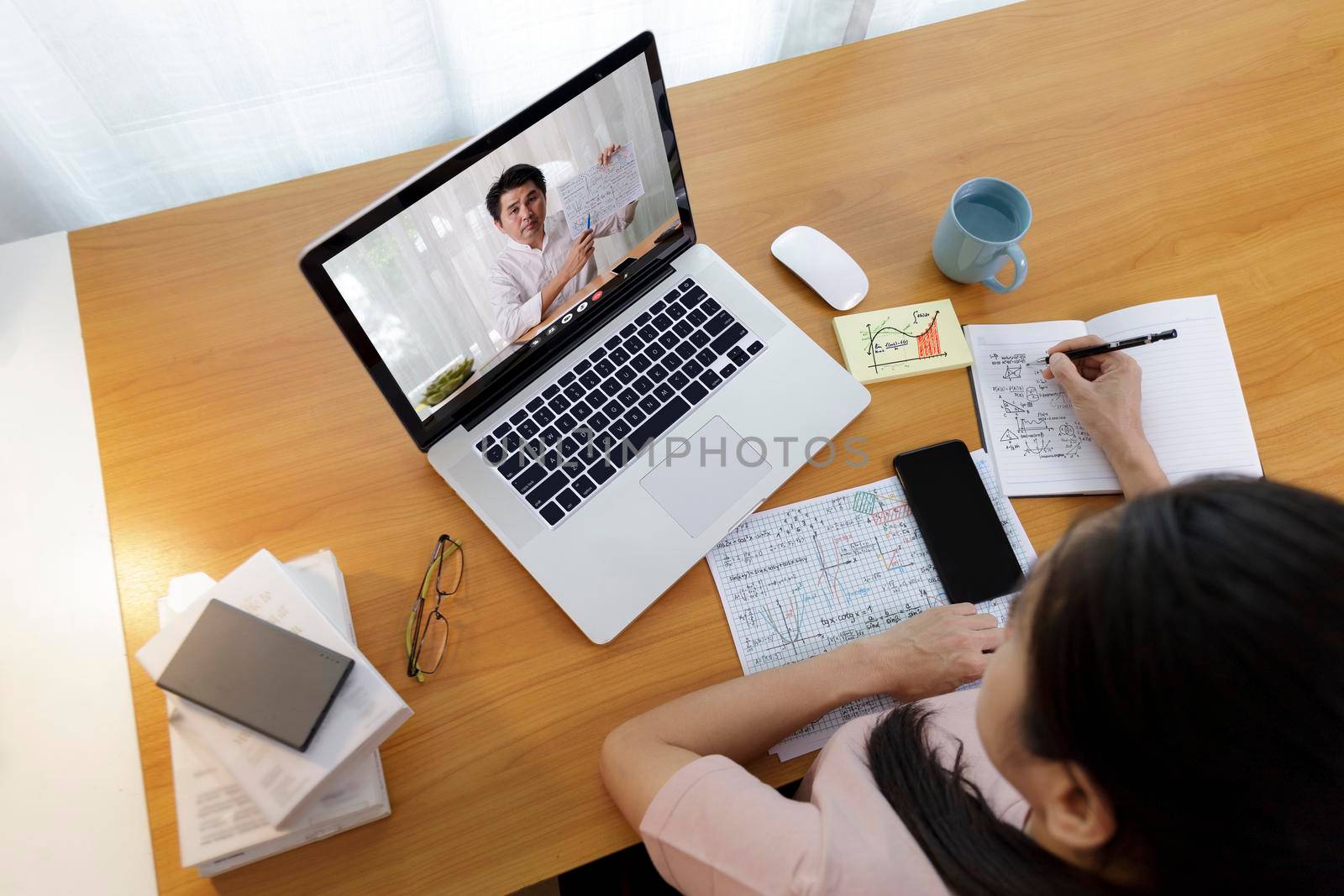 High angle view of video conference with teacher on laptop at home. Top view businesswomen using laptop meeting with colleagues. Covid-19 work from home.,  e-learning education concept. by Satrinekarn