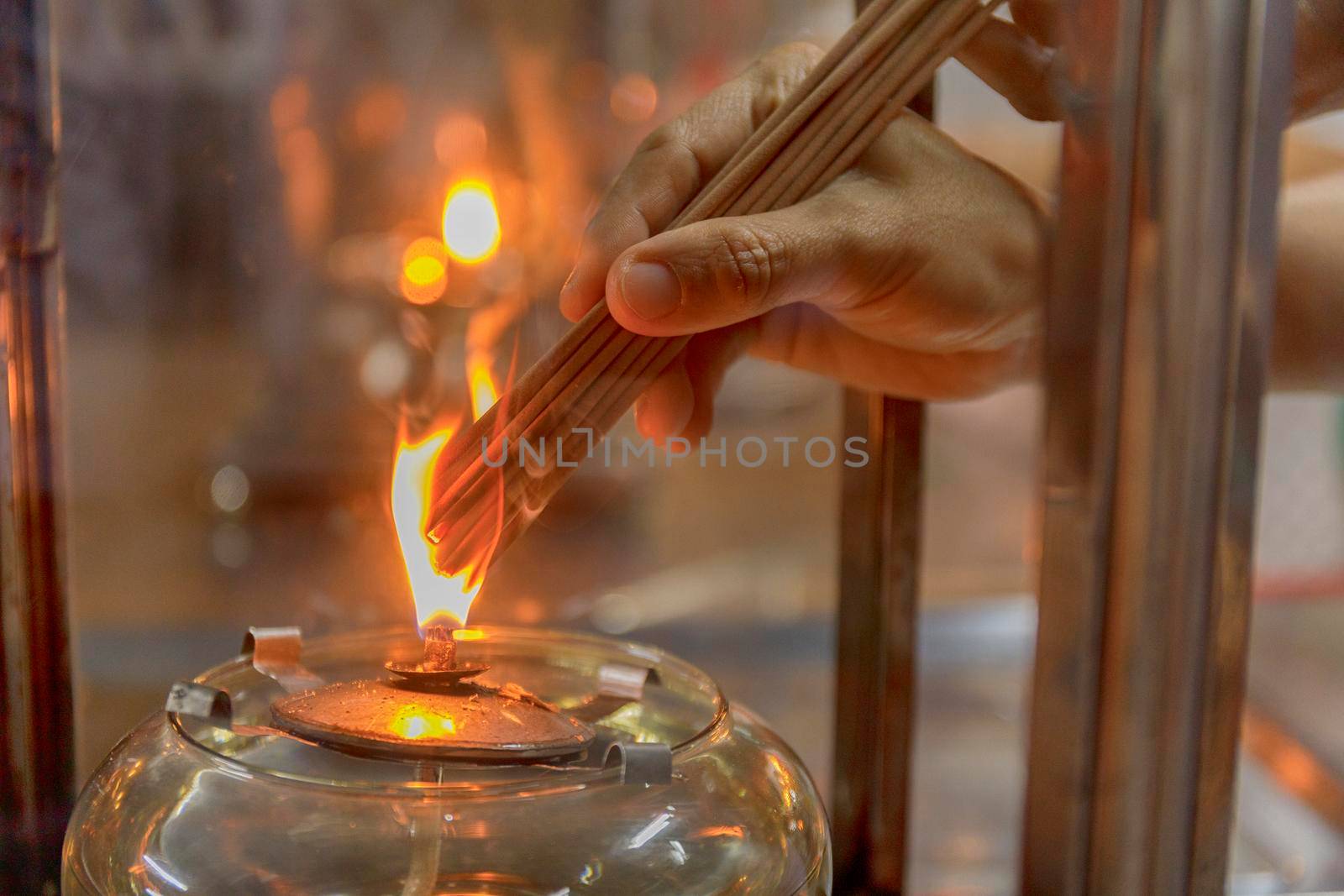 Close up hand cense joss stick with Oil lamp fire. With film grain effect by Satrinekarn