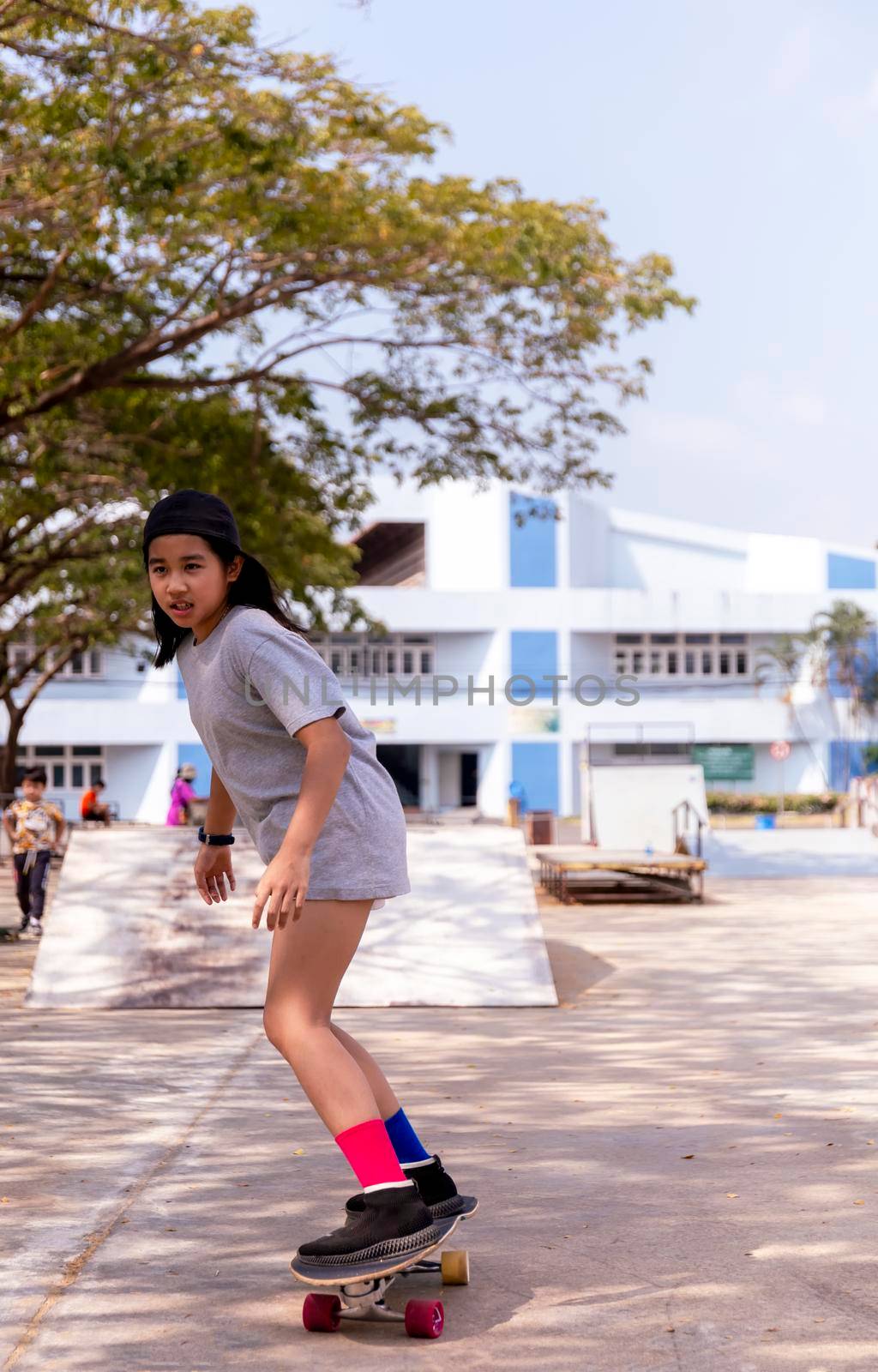 Little asian girl play surf skate board at park skate ramp outdoors on morning. Happy girl play surfskate board at park . Sport activity lifestyle concept