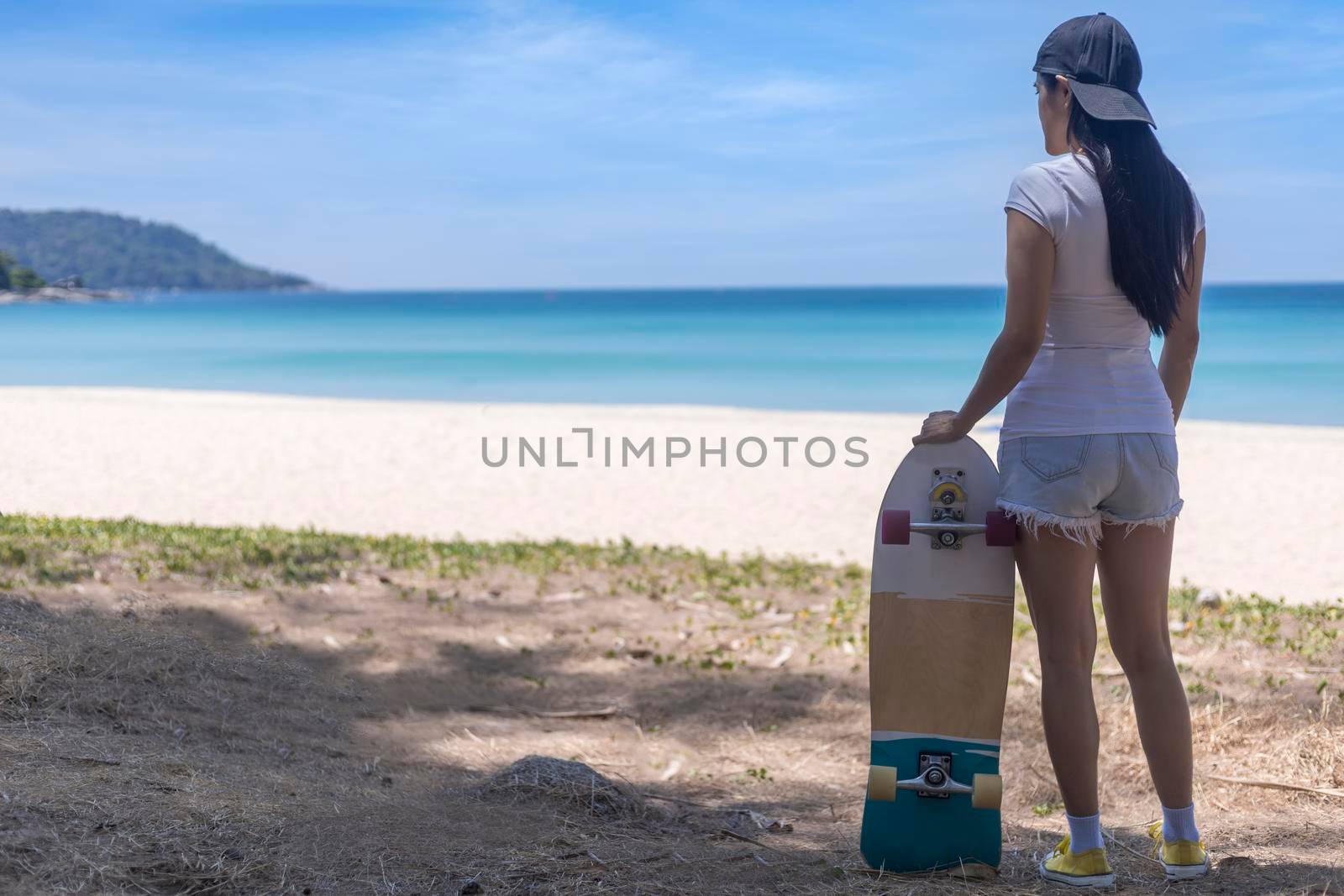 Young women hold surf skate board with beach background. Women stand with surf skate relax and enjoy with tropical beach with copy space
