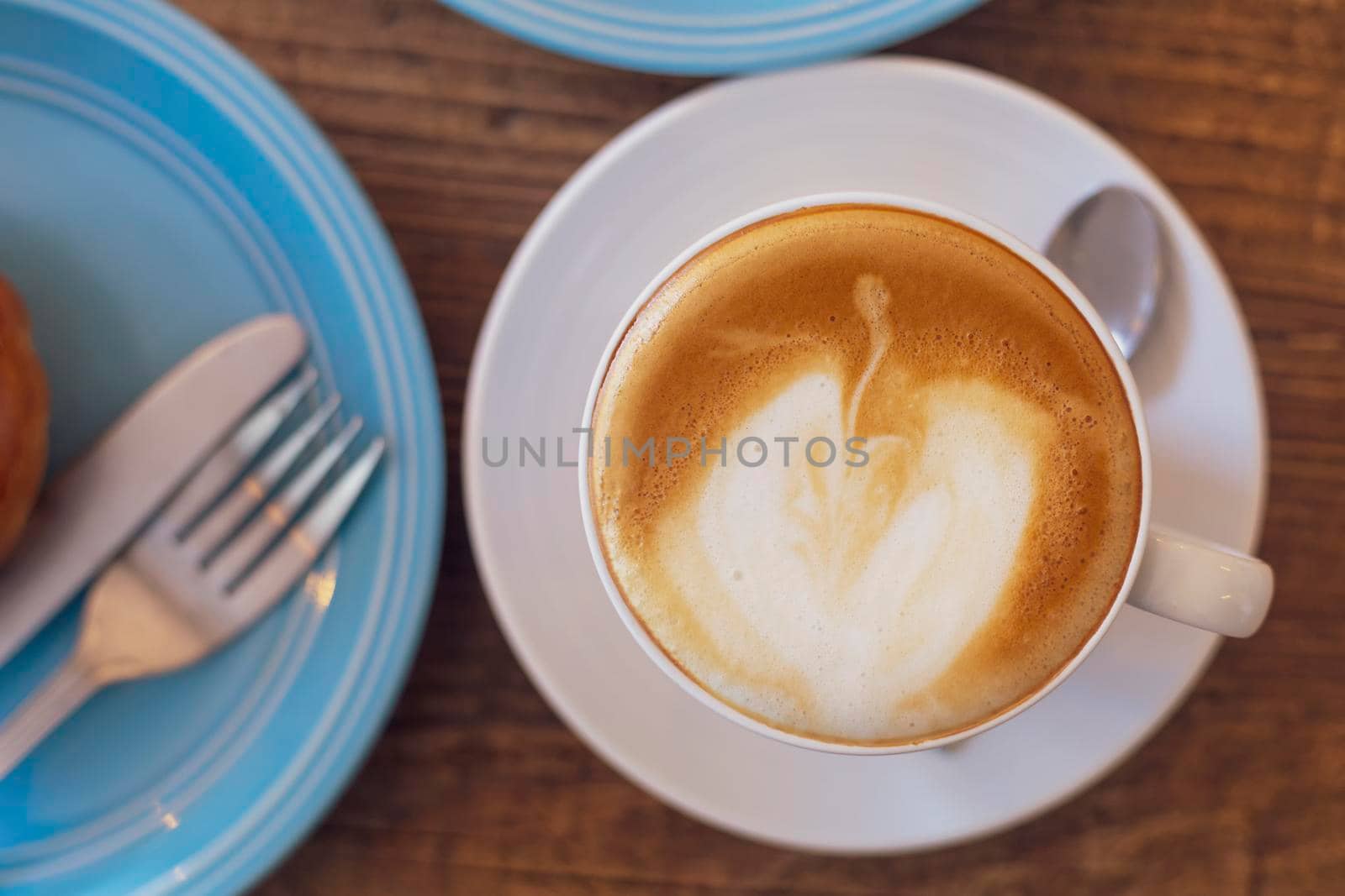 Top view Close up hot cappuccino, latte on table with blur coffee shop background. Hot cappuccino coffee on wood table with blur brakefast background. breakfast at coffee shop. soft focus select coffee