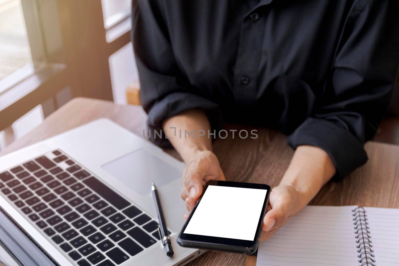 Female hands holding smart phone with blank white screen. Women hands workspace, close-up hand holding smartphone blank screen for text and content at cafe coffee shop