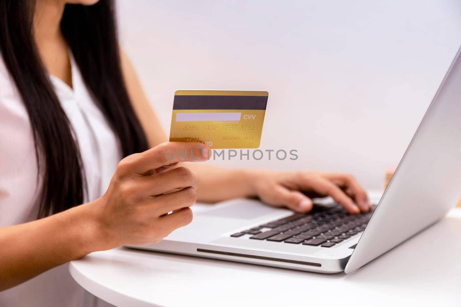 Young woman holding credit card and using laptop computer. Women working at home. Online shopping, e-commerce, internet banking, spending money, working from home concept. Technology shopping online concept.