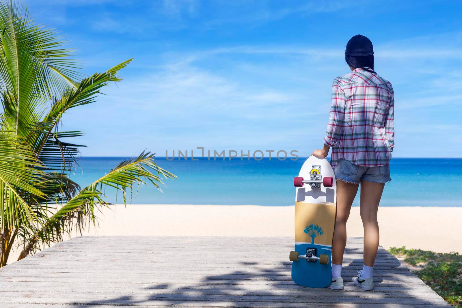 Young women hold surf skate board with beach background. Women stand with surf skate relax and enjoy with tropical beach with copy space