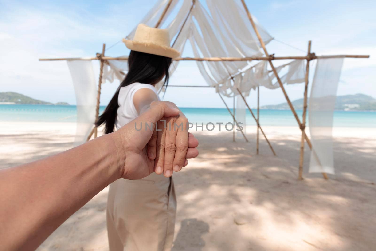 POV Point of view Follow me woman leads boyfriend by hand to the sea,. Close up hands and blur Back view of happy girl walking on beach. Couple holiday travel on beach. Summer vacation.