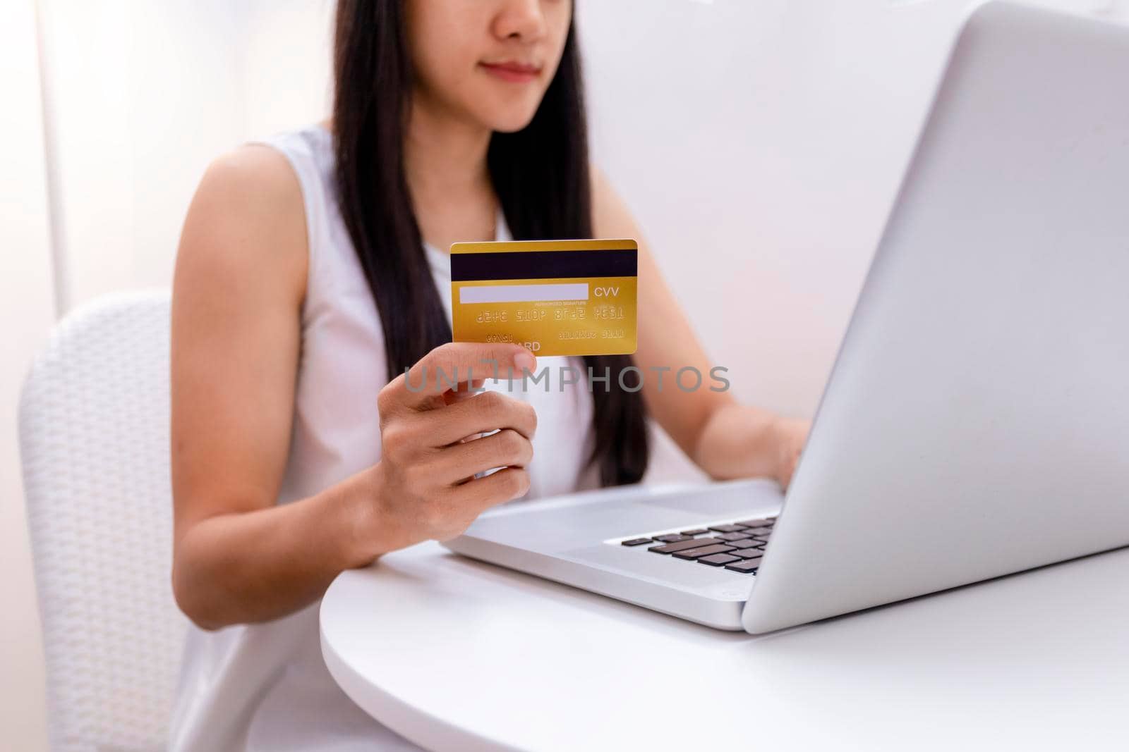 Young woman holding credit card and using laptop computer. Women working at home. Online shopping, e-commerce, internet banking, spending money, working from home concept. Technology shopping online concept.