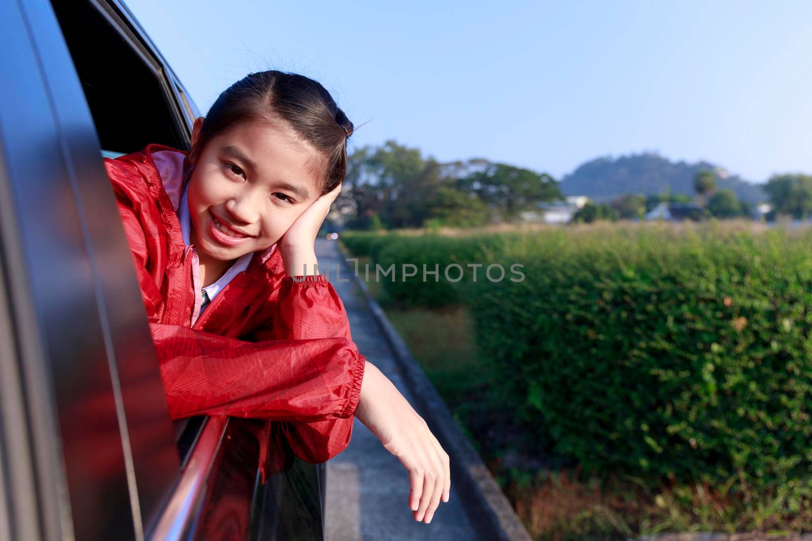 Asian little girl looking something out the car. In the morning, the girl was looking at something outside the car window on the way to school. children relax with street view from the car. Family at car concept.