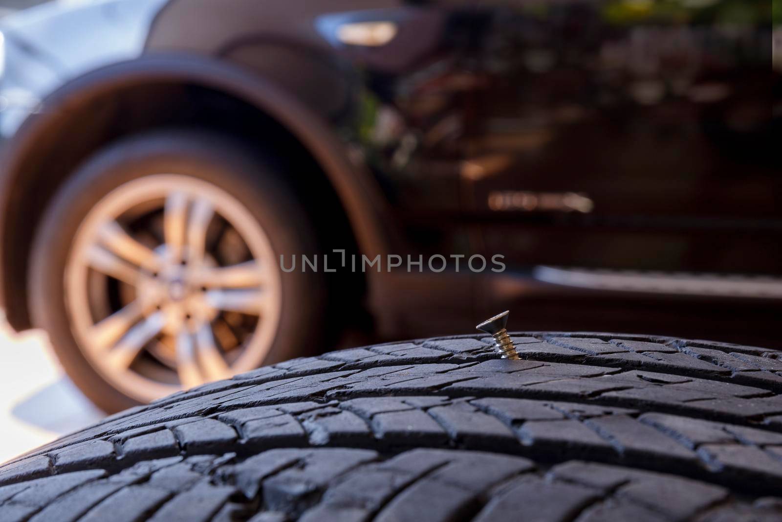 Close up old tire have nails nut or screw drive stuck in side. Tire workshop and change old wheel on the car. Used car tires stacked in piles at tire fitting service repair shop by Satrinekarn