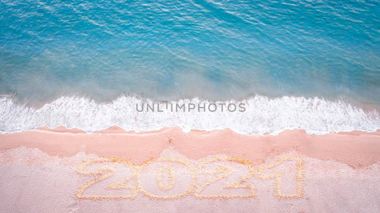 Aerial drone top view happy new year 2021 written on sandy beach sea with copy space. New year concept by Satrinekarn