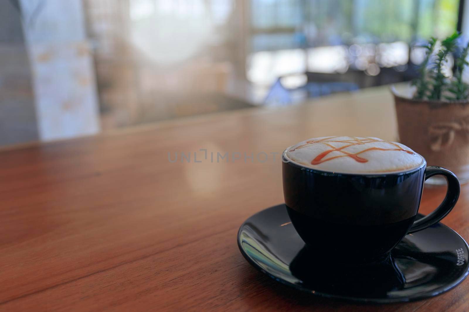 Close up hot cappuccino, latte, caramel macchiato on table with blur coffee shop background. Process with warm vintage tone style. 