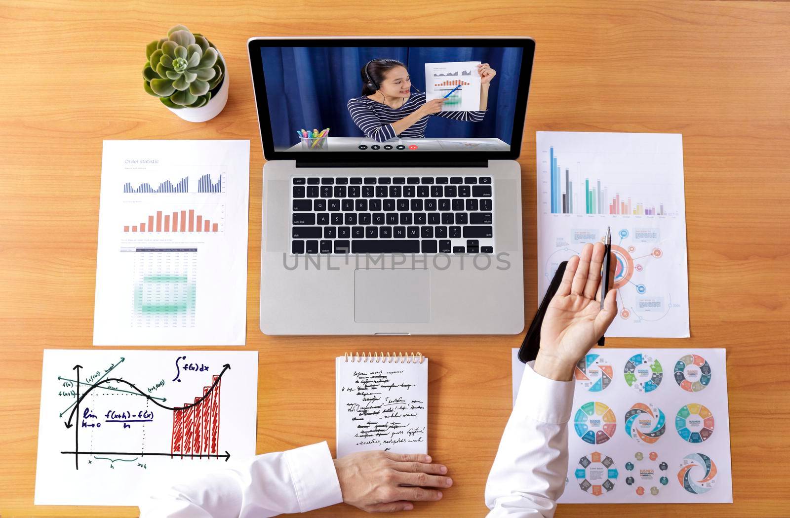 Top view Businessman and businesswoman analysis financial chart with videoconference online meeting. Hand of businesswomen using laptop meeting with diverse colleagues. Covid-19 working from home. 