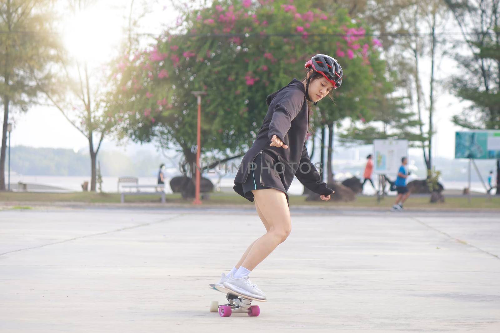 Asian women on skates board outdoors on beautiful summer day. Happy young women play surfskate at park on morning time. Sport activity lifestyle concept
