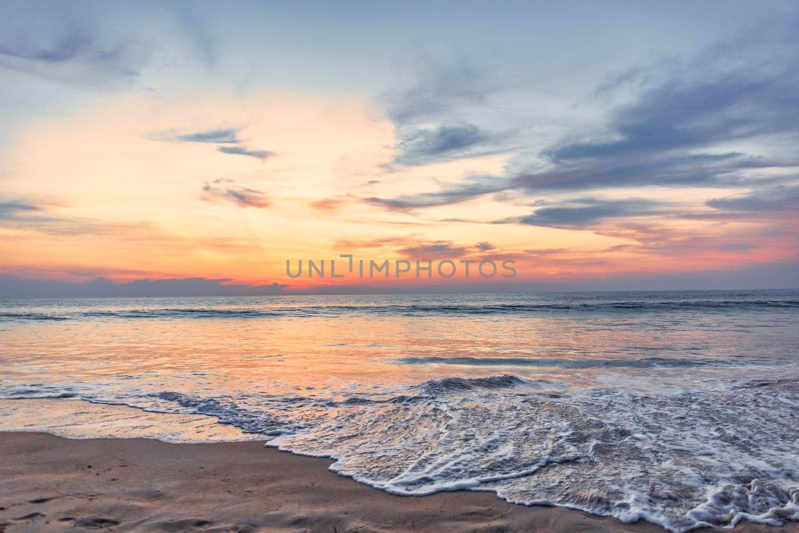 Beautiful sunset over the clam sea with cloud and sky background. Sunset over tropical beach. Nature summer  concept. Peak sunset over sea with yellow light reflect in cloud.